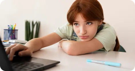 Teen girl distracted on a laptop with her notebook and pencil next to her